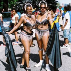 Two women in feathered carnival costumes holding flags