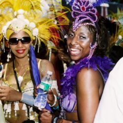 Women in colorful carnival costumes smiling joyfully.