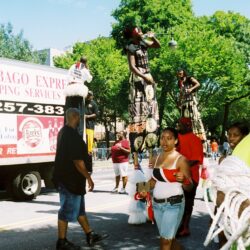People on stilts in a street parade.