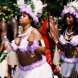 Women dancing in vibrant, colorful costumes parade.