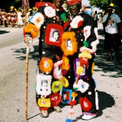 Two people in colorful, festive costumes outdoors.