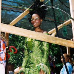Woman in green dress with feathered headpiece.