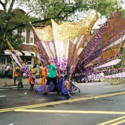 Carnival float with colorful wings on street.