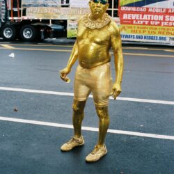 Man in gold body paint on street.