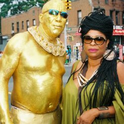 Man painted gold with woman in green.