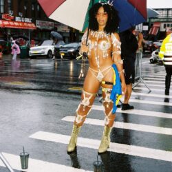 Carnival costume woman with umbrella on street.