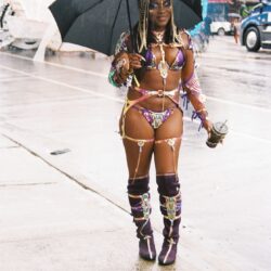 Carnival dancer with umbrella in rain.