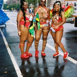 Three women in vibrant carnival costumes outdoors.