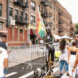Person on stilts holding a flag outdoors.