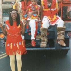People in colorful feathered costumes on float