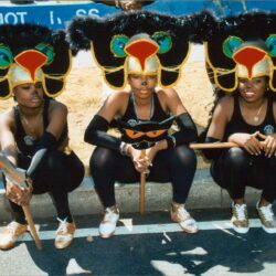 Three women in colorful bird carnival headdresses