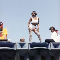 Woman posing atop large speakers at outdoor concert
