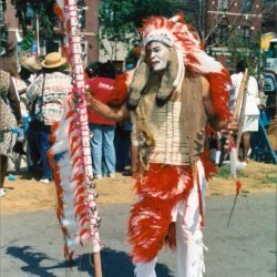 Person in feathered headdress and red regalia