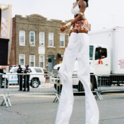 Stilt performer in white pants and colorful skirt