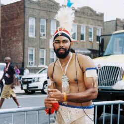 Person in feathered carnival costume on street