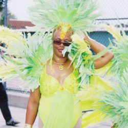 Person in lime carnival costume wearing feathered headdress