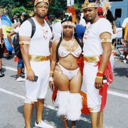 Three people in colorful feathered carnival costumes